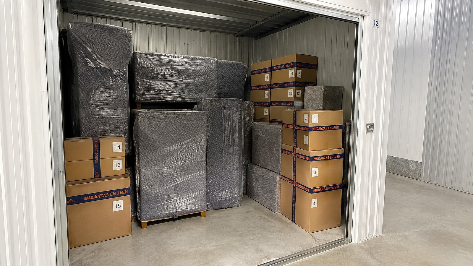 Interior del guardamuebles de Mudanzas en Jaén con muebles tapados con mantas acolchadas y cajas etiquetadas